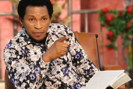 a man with sitting in a chair, wearing a white and black floral shirt