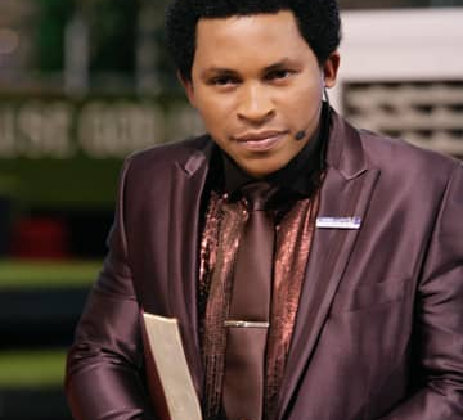 A man in a brown suit and a tie is looking at the camera